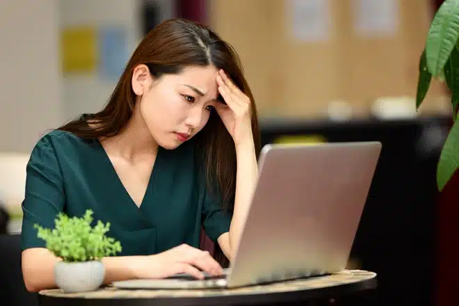 A woman pondering while looking at a computer